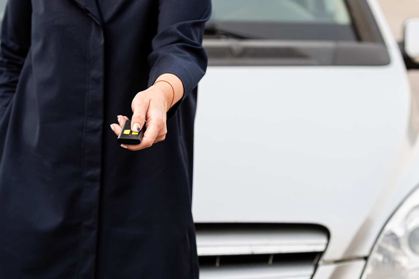 Una persona con abrigo negro sosteniendo un mando a distancia de coche.